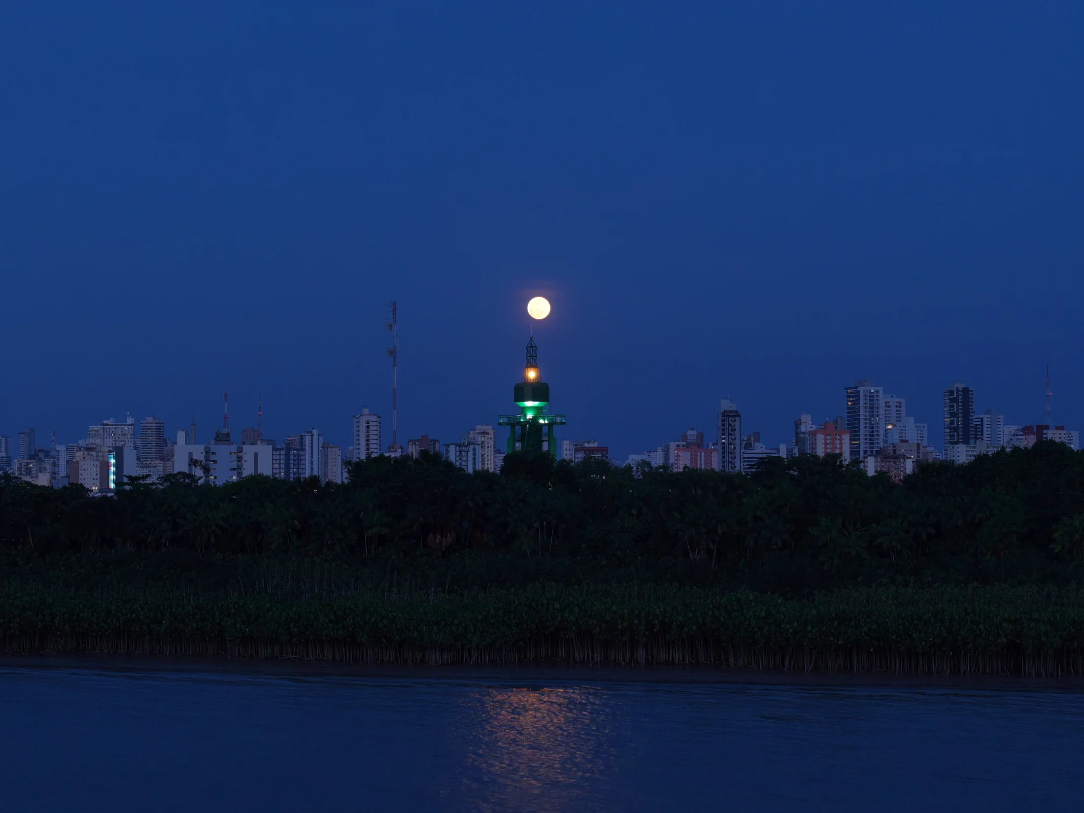 Fotografia aérea de Belém ao anoitecer, com a lua sobre um edifício e o rio ao fundo